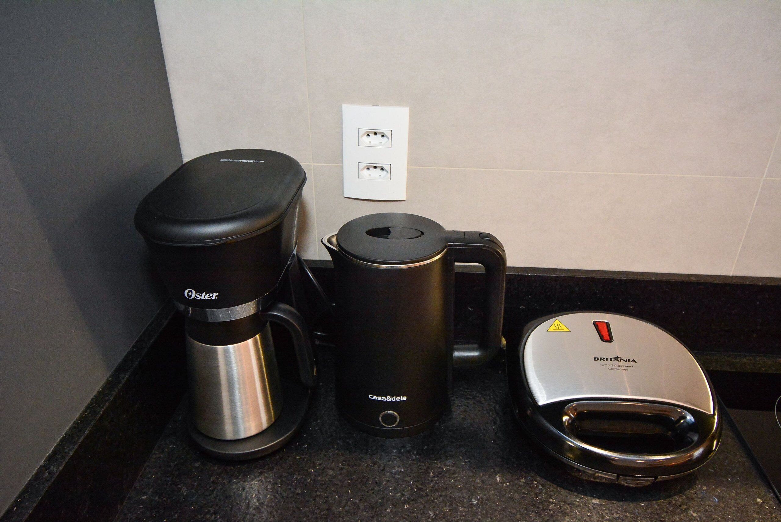 A kitchen with a coffee maker, a kettle, and a toaster.