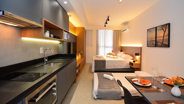 Une chambre d’hôtel moderne dotée d’une kitchenette, d’un lit avec vue et d’un coin repas.