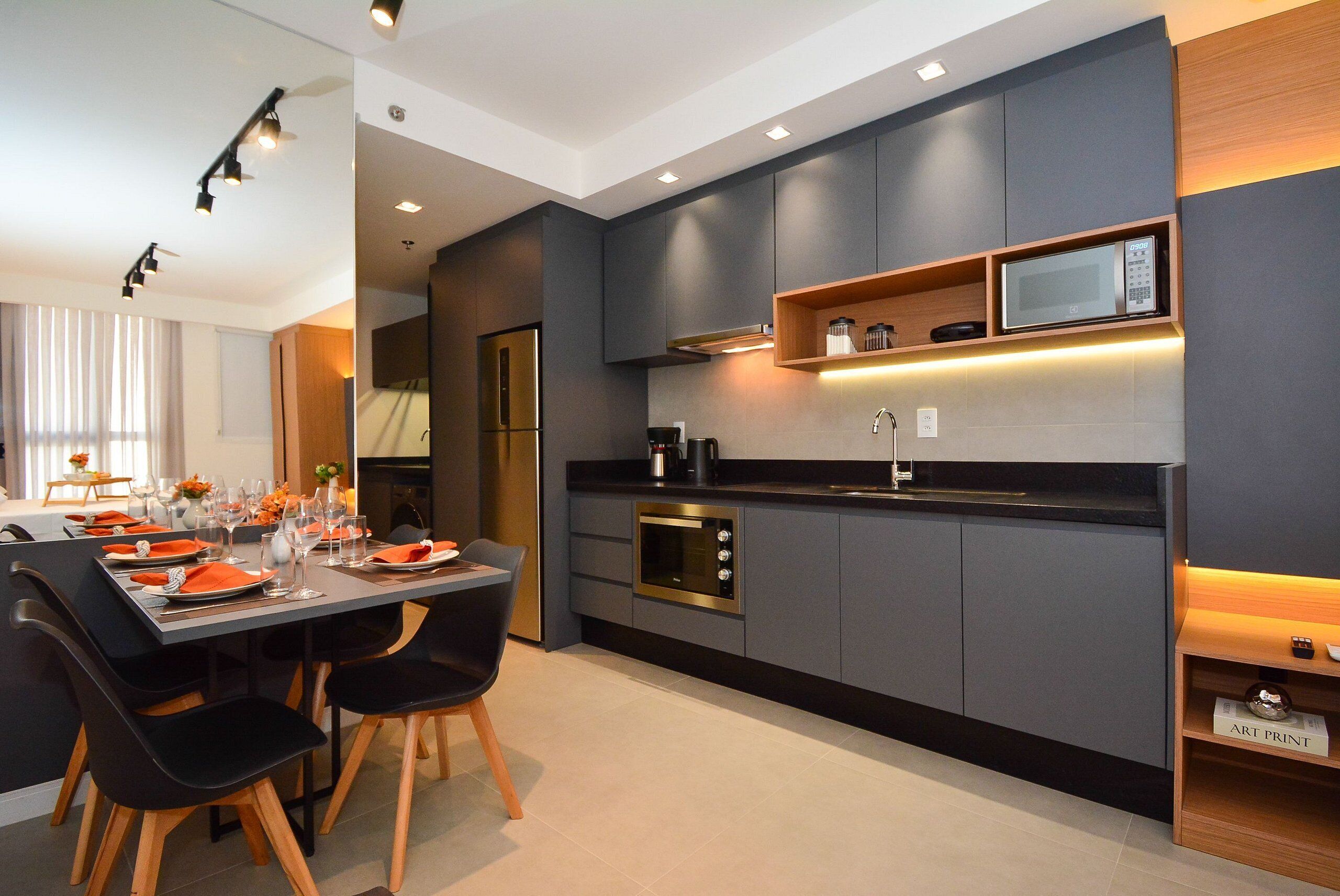 A modern kitchen with built-in appliances, a dining area with a table set for two, and a small shelf with a microwave.