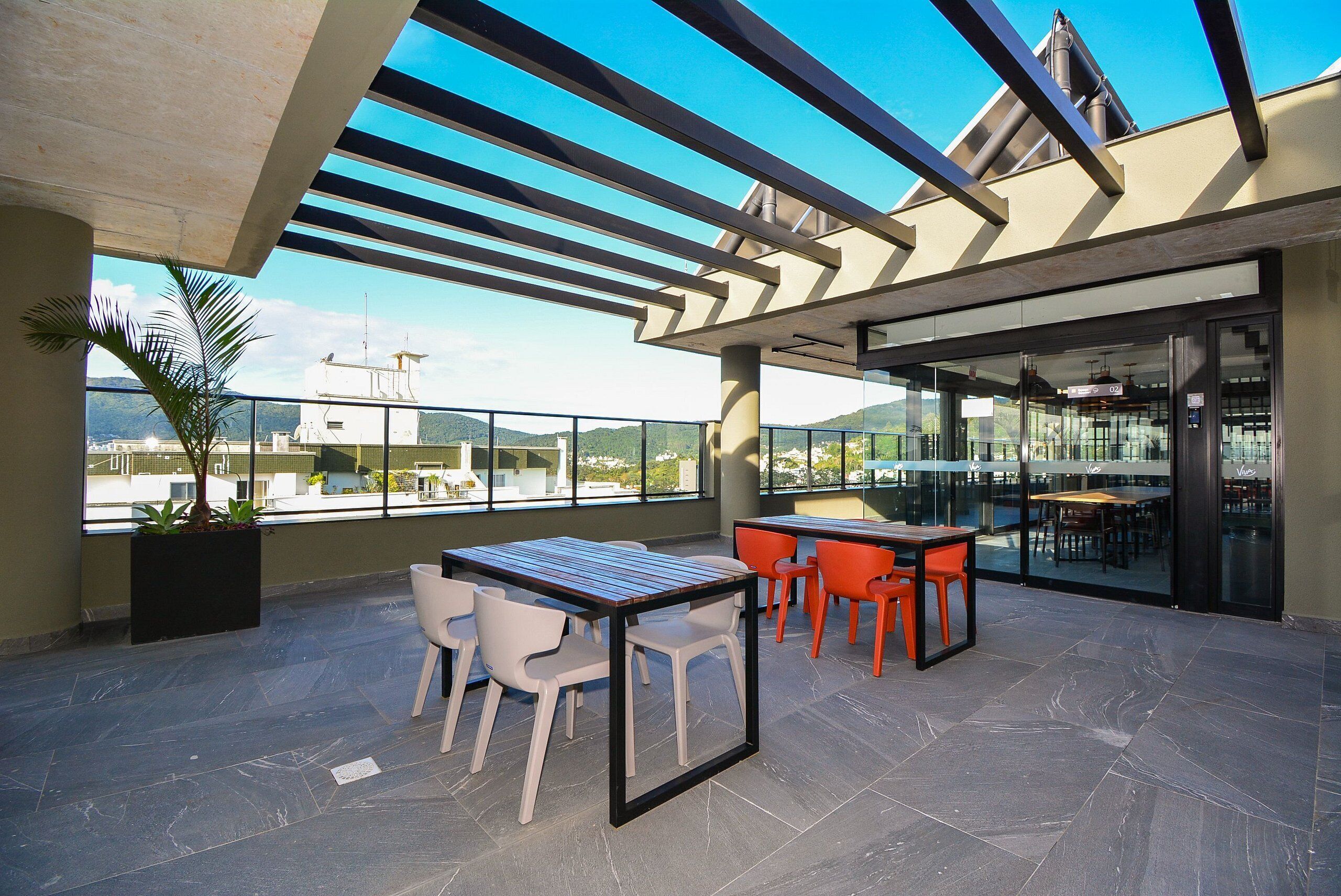 An outdoor terrace with a table and chairs, a potted plant, and a view of the cityscape.