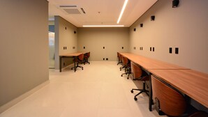 Une salle de conférence dotée de longues tables et de chaises, d’un sol carrelé et d’un éclairage encastré.
