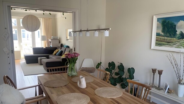 Zona pranzo con tavolo in legno, sedie e un vaso di fiori.