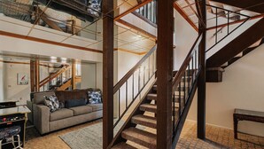 A multi-level living space with a staircase, a sofa, and a gaming console. - Golden Hour | Jacuzzi, Sauna, Pool, Tennis, Gated! (Big Bear Lake)