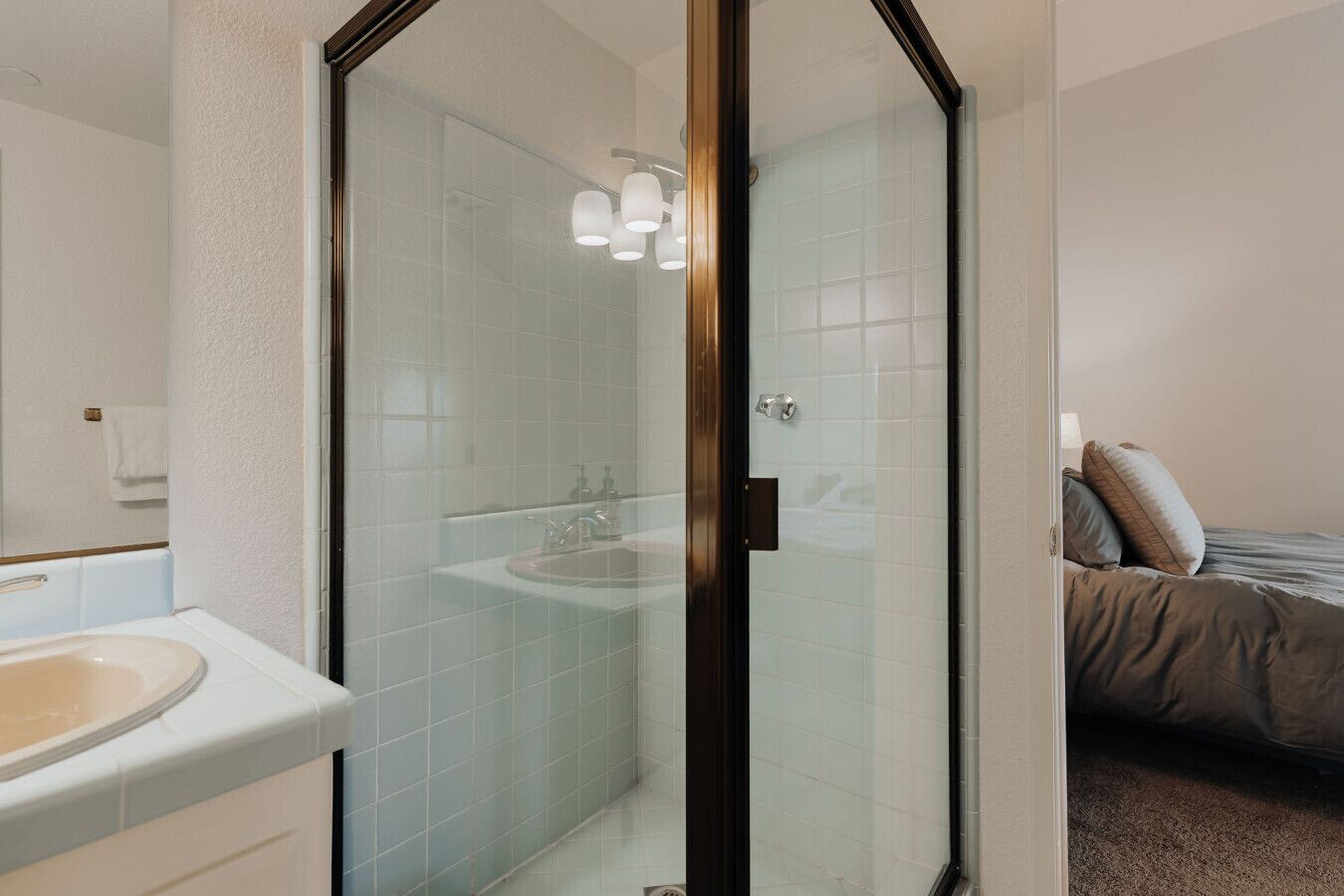 Een moderne badkamer met een douchecabine van glas, een wastafel en een spiegel.