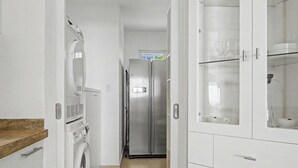 Ein Waschraum mit Waschmaschine, Trockner und einem Edelstahl-Kühlschrank.