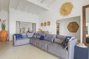 A living room with a grey sectional sofa, a large vase, and decorative wall art.
