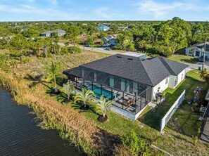 Une maison moderne dotée d’une piscine à débordement, entourée d’une végétation luxuriante et offrant une vue sur le quartier.