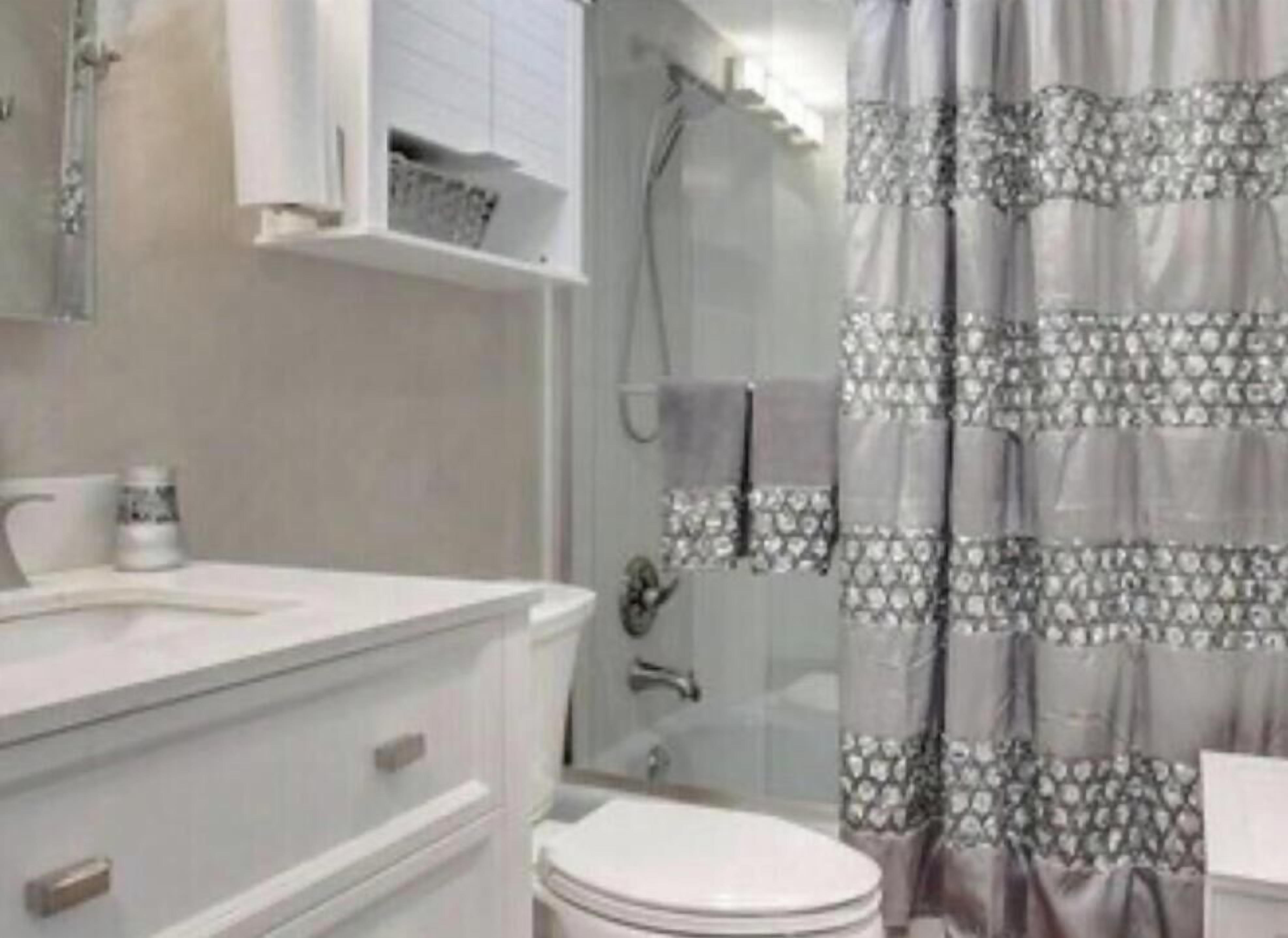 A bathroom with a toilet, a sink, a mirror, and a shower curtain.