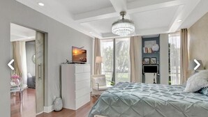Une chambre à coucher avec un lit, un bureau, une chaise, un lustre et une fenêtre avec des rideaux.