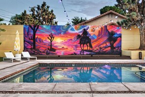 A pool area with a mural, lounge chairs, and a house in the background. - Desert Gold House By Homestead Modern (Yucca Valley)