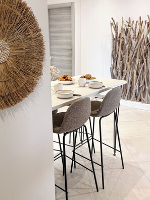 A dining area with a light-colored table, four grey chairs, and a decorative wall piece. - Villa Azzura 130m2 with swimming pool (Cauro)