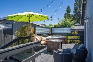 En terrasse med udendørs møbler, jacuzzi og lysslinger.