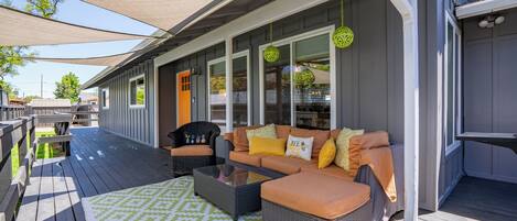 Terraza exterior con sofá y sillones, un tapete estampado y un área cubierta con pérgola.