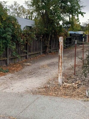A gravel path leading to a wooden fence with a metal gate.