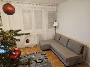 A living room with a grey sofa, a Christmas tree, and a radiator. - Apartman FITT - Apartman (Zagreb)
