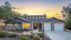 Una casa a due piani con garage, un portico coperto e un giardino anteriore curato.
