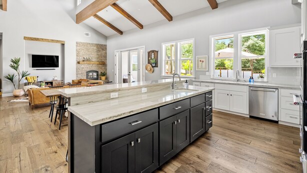 Un'ampia cucina con un'isola grande, travi in legno al soffitto e un camino in pietra.
