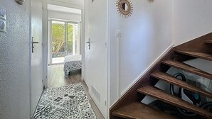 Un pasillo con piso estampado, una escalera de madera y decoración en las paredes.