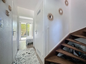 Un couloir doté d’un revêtement de sol à motifs, d’un escalier en bois et d’œuvres d’art décoratives sur les murs.