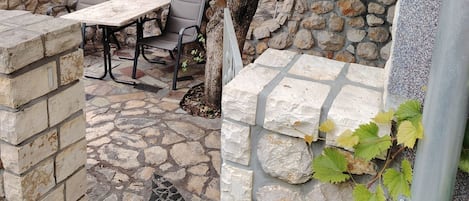 Un patio al aire libre con paredes de piedra, una mesa y sillas.