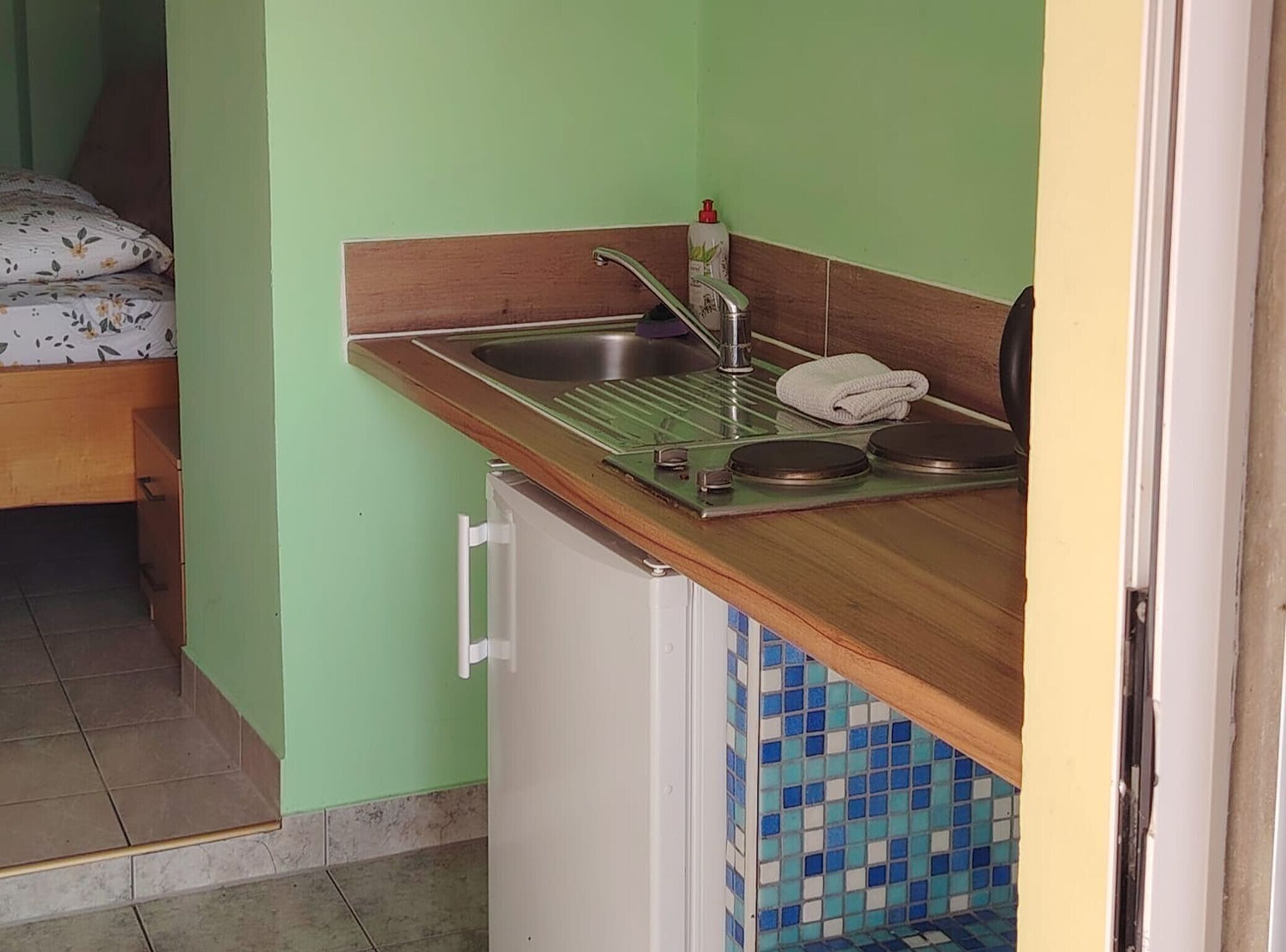 A small kitchenette with a sink, a faucet, a soap dispenser, and a towel.