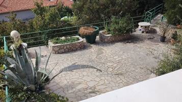 A stone patio with planters, a railing, and a view of boats in the background.