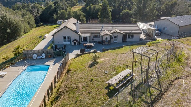 Um imóvel residencial com piscina, mobiliário de jardim e uma casa grande com vários quartos.