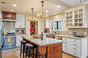A kitchen with a central island, white cabinetry, and a red washing machine.
