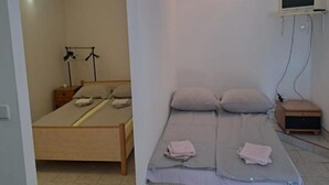 A bedroom with a single bed, a bedside table, a TV mounted on the wall, and a small wooden cabinet. - Americana Karlobag Apartments - One Bedroom Apartment with Terrace (Karlobag)