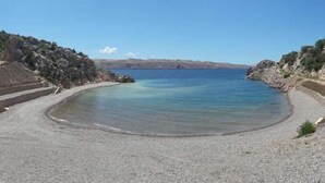 A pebble beach with a clear blue sea, rocky terrain, and a distant view of the coastline. - Americana Karlobag Apartments - One Bedroom Apartment with Terrace (Karlobag)
