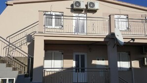 Een gebouw met twee airconditioners, een balkon en een schotelantenne.