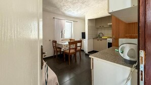 Et kompakt køkken med spiseplads, et lille vindue og en loftlampe.