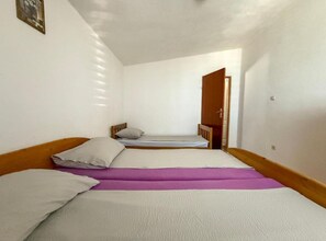 A small, single-room accommodation with two beds, a wooden door, and a white wall. - Americana Karlobag Apartments - Comfort One Bedroom Apartment with Terrace (Karlobag)