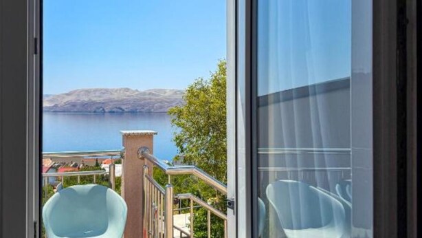 En balkon med udsigt over et sølandskab og fjerne bakker.