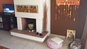A living room with a fireplace, a television, and a decorative wall piece. - Magic mola (Chalkidiki)