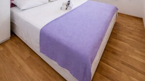 A bed with a white mattress and a purple blanket, a toy car on the bed, and wooden flooring. - Apartments Anita - One bedroom apartment with terrace (Stobrec)