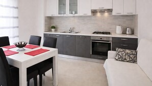 A modern kitchen with white cabinets, a gas stove, and a sink. - Apartments Anita - One bedroom apartment with terrace (Stobrec)
