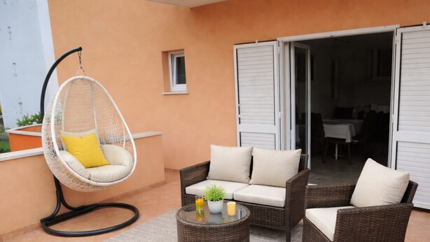 A patio with wicker furniture, a hanging chair, and a small table with a plant and drink. - Apartments Anita - One bedroom apartment with terrace (Stobrec)