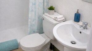 A bathroom with a toilet, sink, and shower curtain. -  Entire private apartment near the airport- perfect for layovers andarrivals (Panamá)