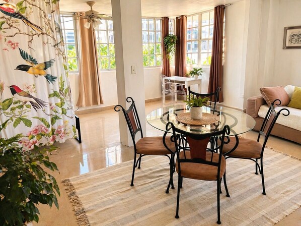 Une pièce spacieuse comprenant une table à manger, des chaises, un canapé et de grandes fenêtres.