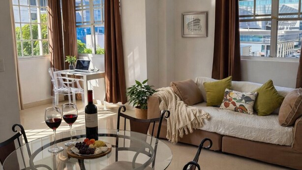 A modern living room with a glass dining table, a sofa, and a view of the city. -  Entire private apartment near the airport- perfect for layovers andarrivals (Panamá)