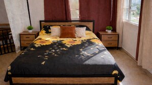 A bedroom with a large bed, two bedside tables with potted plants, a window with curtains, and a view of buildings outside. -  Entire private apartment near the airport- perfect for layovers andarrivals (Panamá)