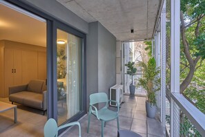 Un balcón con sofá, sillas y plantas en macetas.