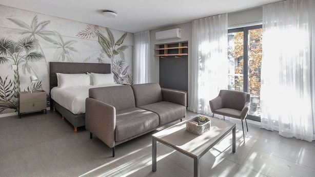 A modern hotel room with a bed, sofa, armchair, and a coffee table. - Alma Rentals Sol Palermo (Buenos Aires)