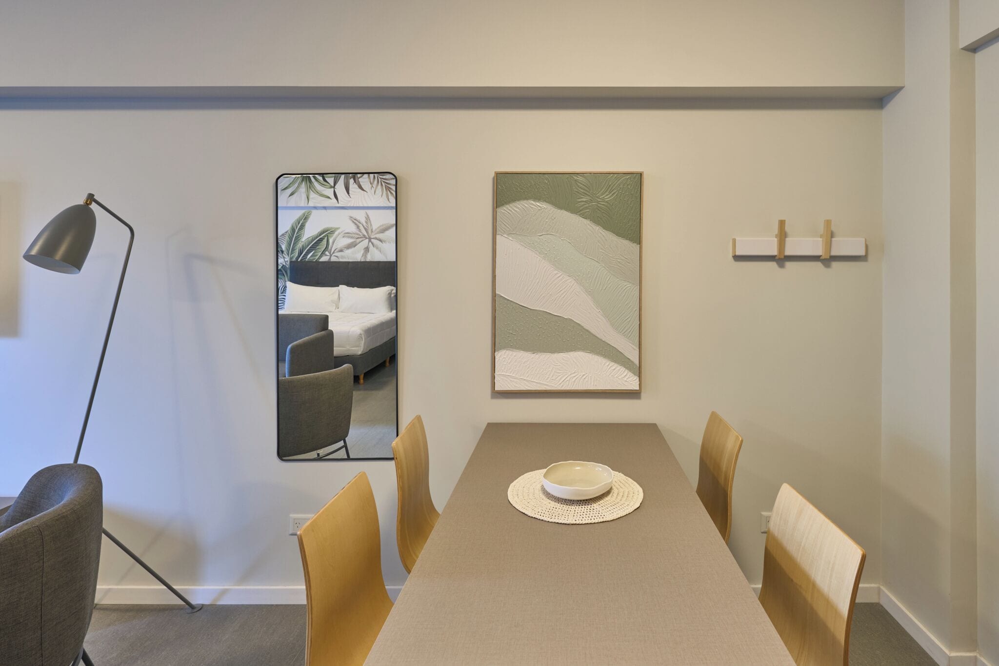 A dining area with a table, chairs, a lamp, and artwork on the walls.