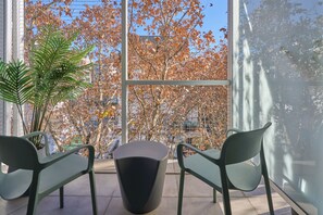 Un espacio interior moderno con asientos y vistas a árboles otoñales a través de un ventanal.