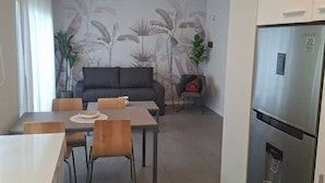 A modern kitchen with a refrigerator, dining table, and chairs. There is a sofa and a plant in the background. - Alma Rentals Sol Palermo (Buenos Aires)