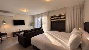 A modern hotel room with a large bed, a flat-screen TV, a desk with a lamp, and a plant. - Alma Rentals Sol Palermo (Buenos Aires)