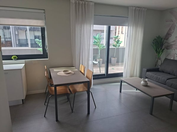Una sala de estar moderna con una mesa de comedor, sillas, un sofá y una mesa de centro.