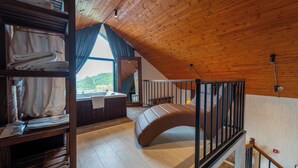 Un dormitorio tipo loft con una cama litera, un ventanal con cortinas y vistas a un paisaje verde.